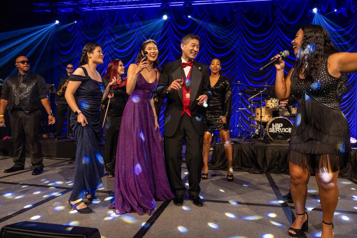 Band singers performing together on stage under blue gala lights