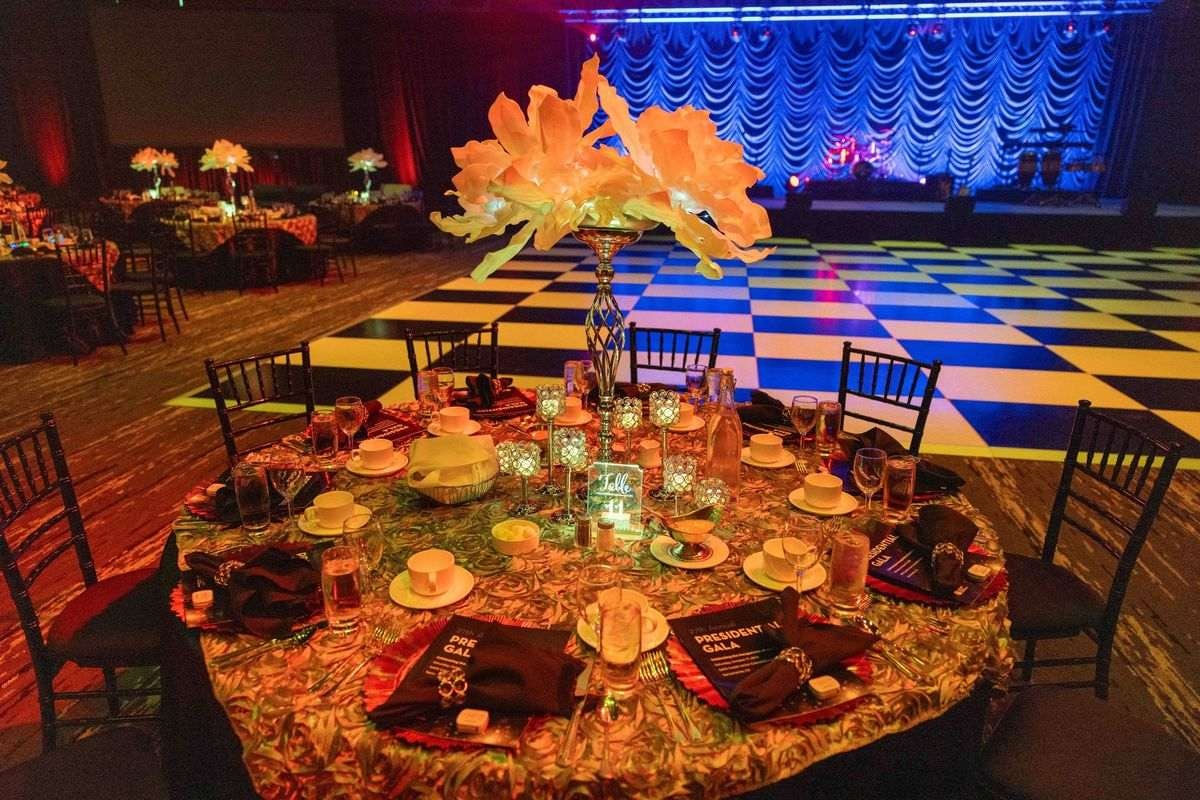 Glowing dinner table with a flower centerpiece and a checkerboard dance floor behind