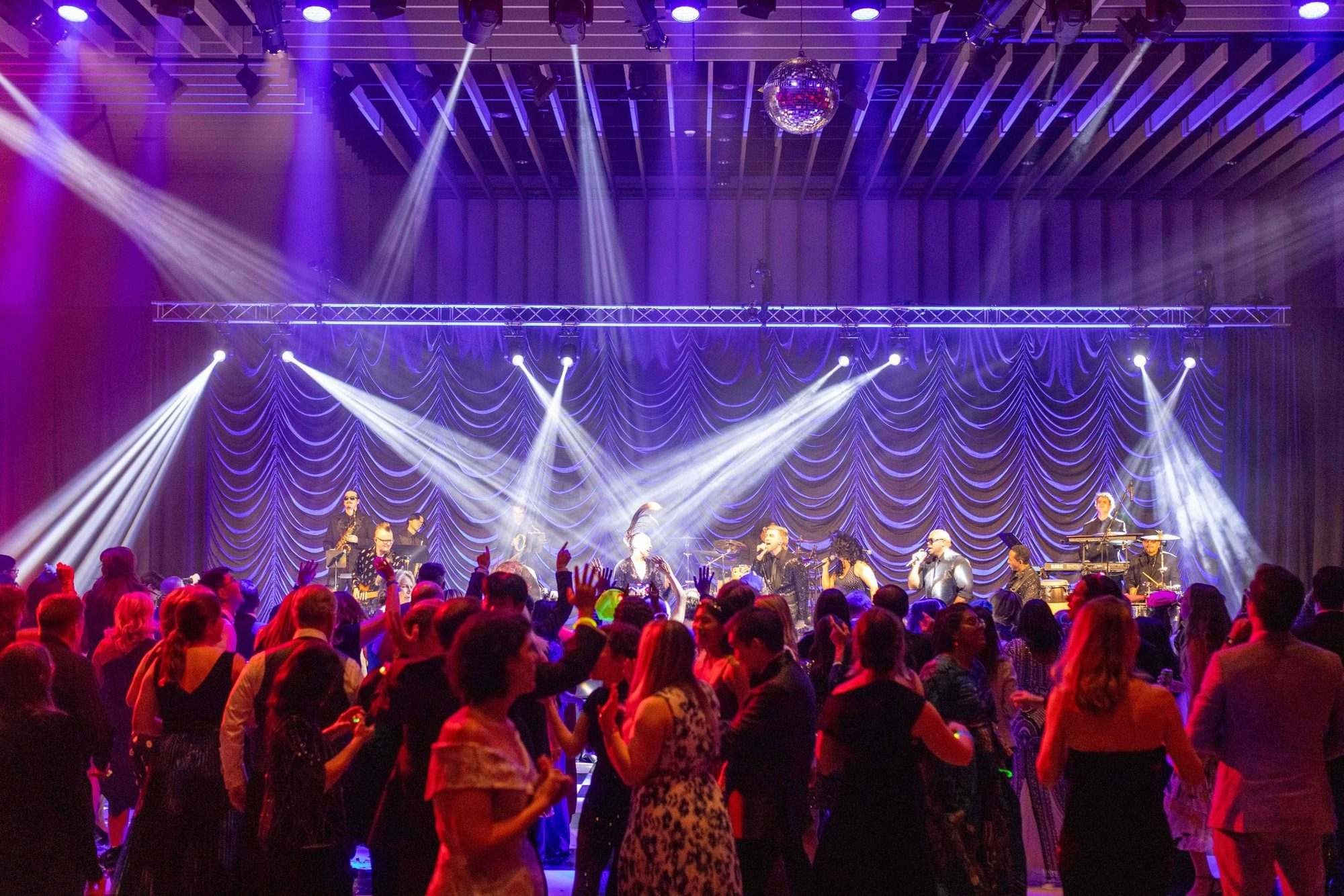 Stage lights sweeping over a packed dance floor at the California Medical Association Presidential Gala in Sacramento