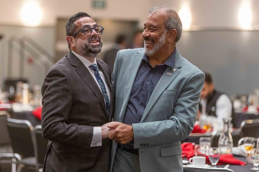 Two attendees laughing and shaking hands while networking at a California hospitality conference — corporate event photography by Michael Pegram