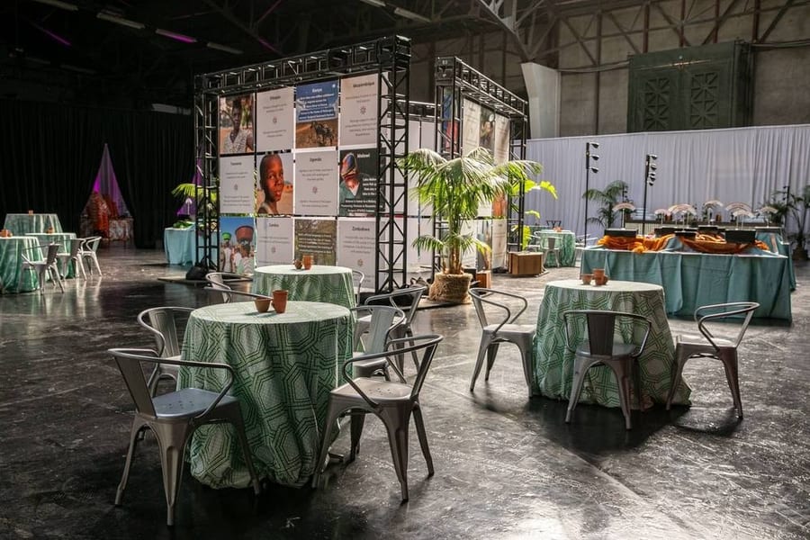 Event space set for a corporate reception with green linens, plants and exhibit displays — corporate event photography by Michael Pegram