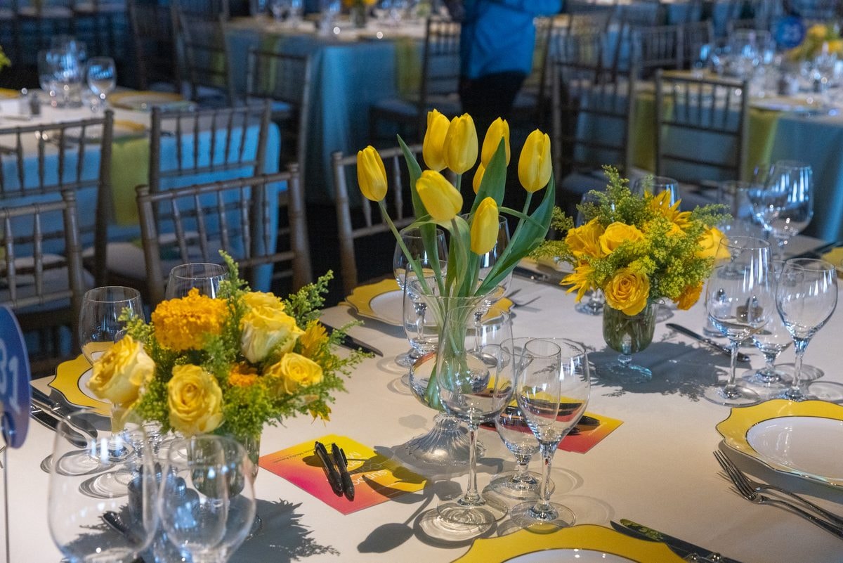 Yellow tulip centerpieces on a gala dinner table set for an awards dinner in San Francisco — corporate event photography by Michael Pegram