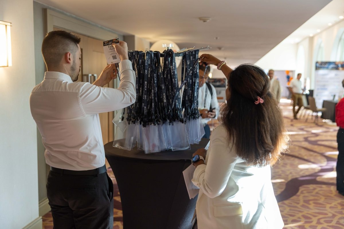 Conference staff hanging attendee lanyards at registration for a California association conference — corporate event photography by Michael Pegram
