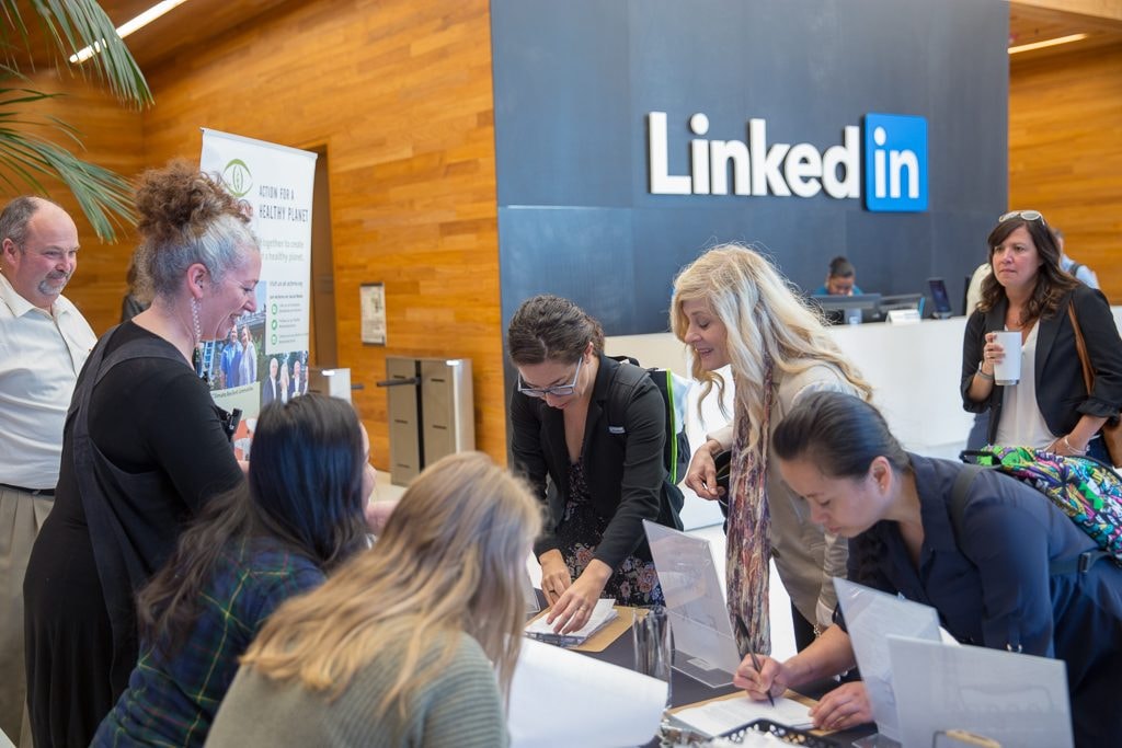 Attendees working together at a table in front of the LinkedIn logo during a workshop at LinkedIn headquarters — corporate event photography by Michael Pegram