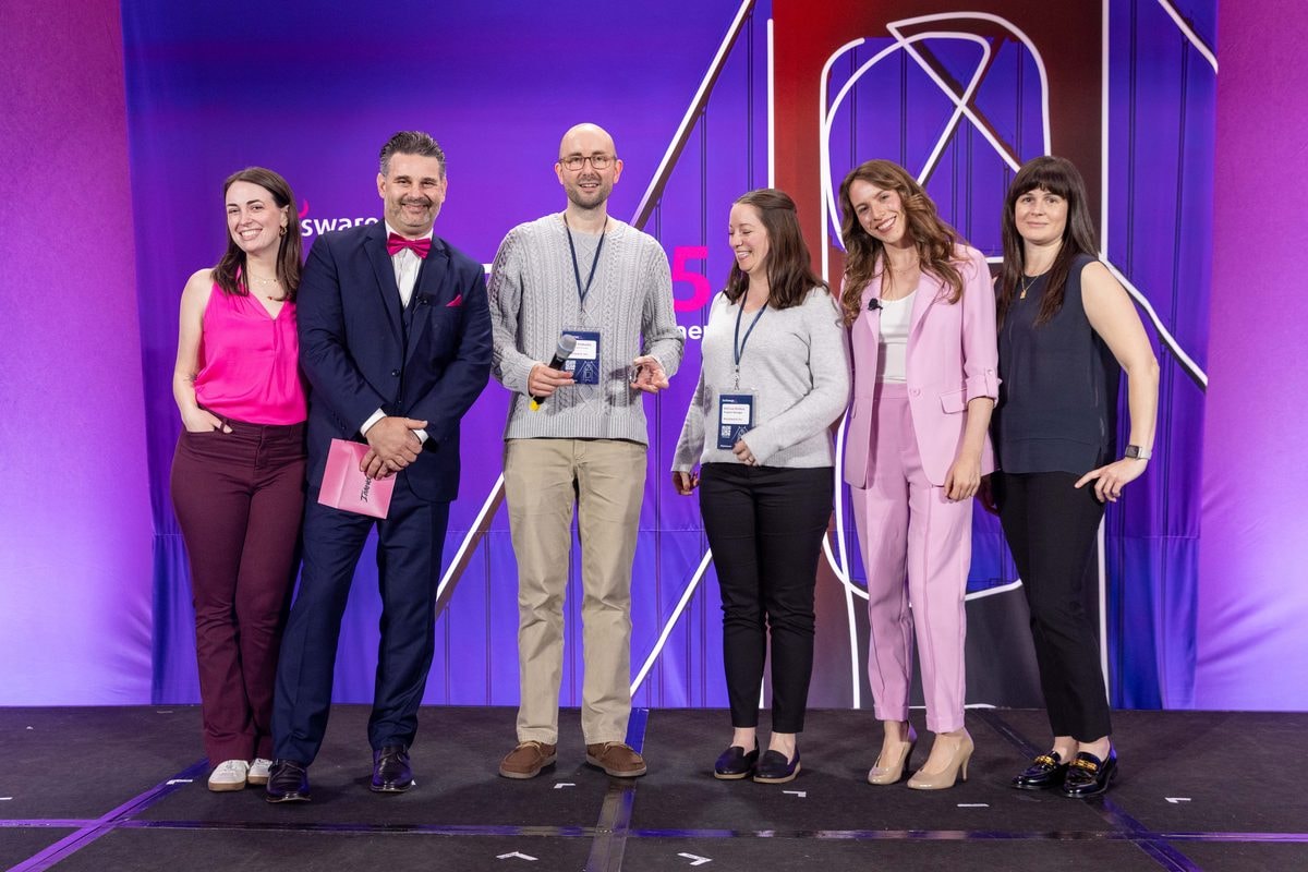 Award winners posing with their trophies on stage at the Planisware Exchange awards dinner — corporate event photography by Michael Pegram